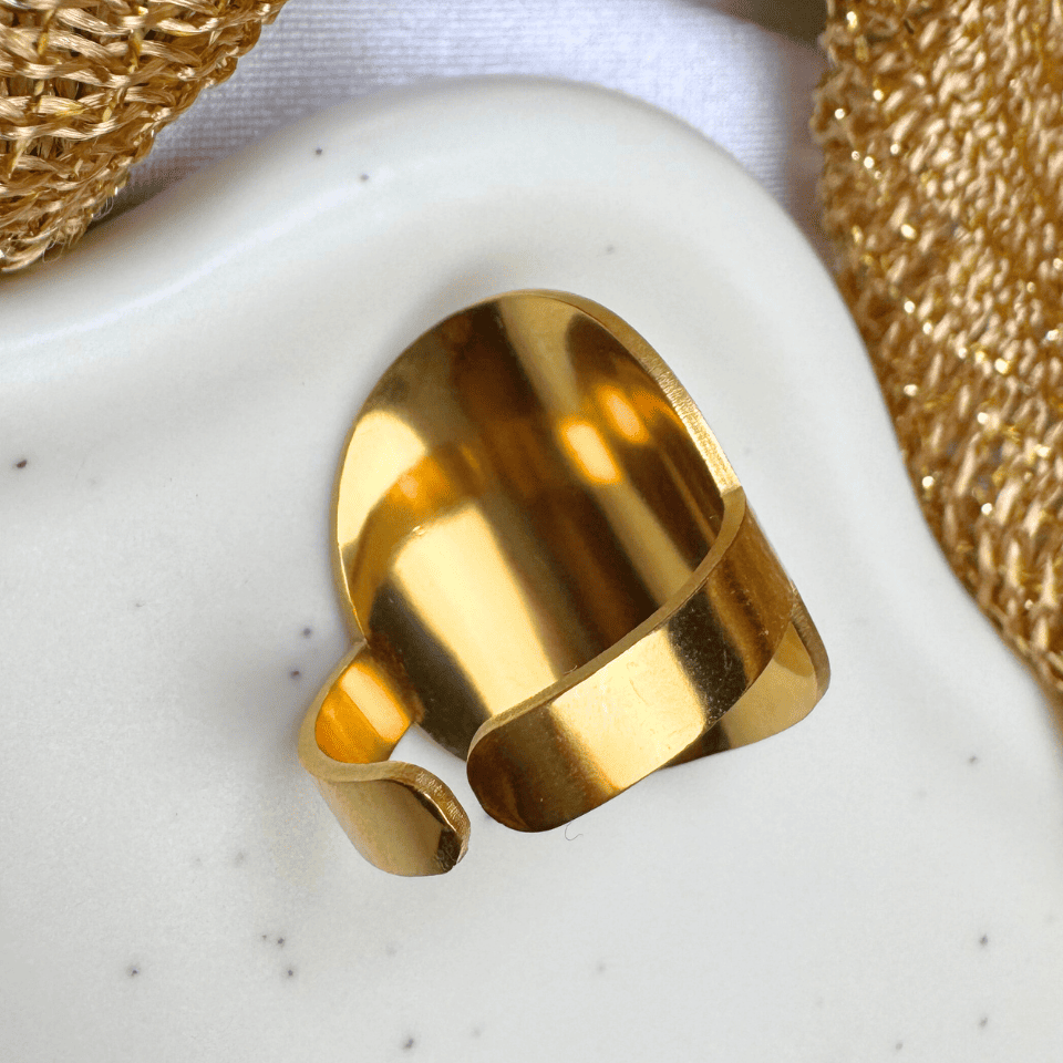 Gold ring on a textured white surface with gold mesh in the background