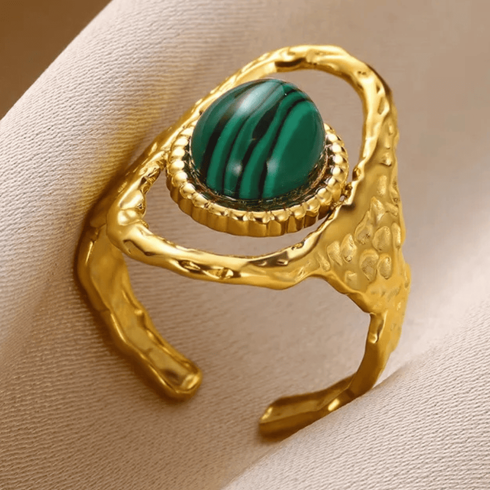 Gold ring with a green gemstone on a beige background