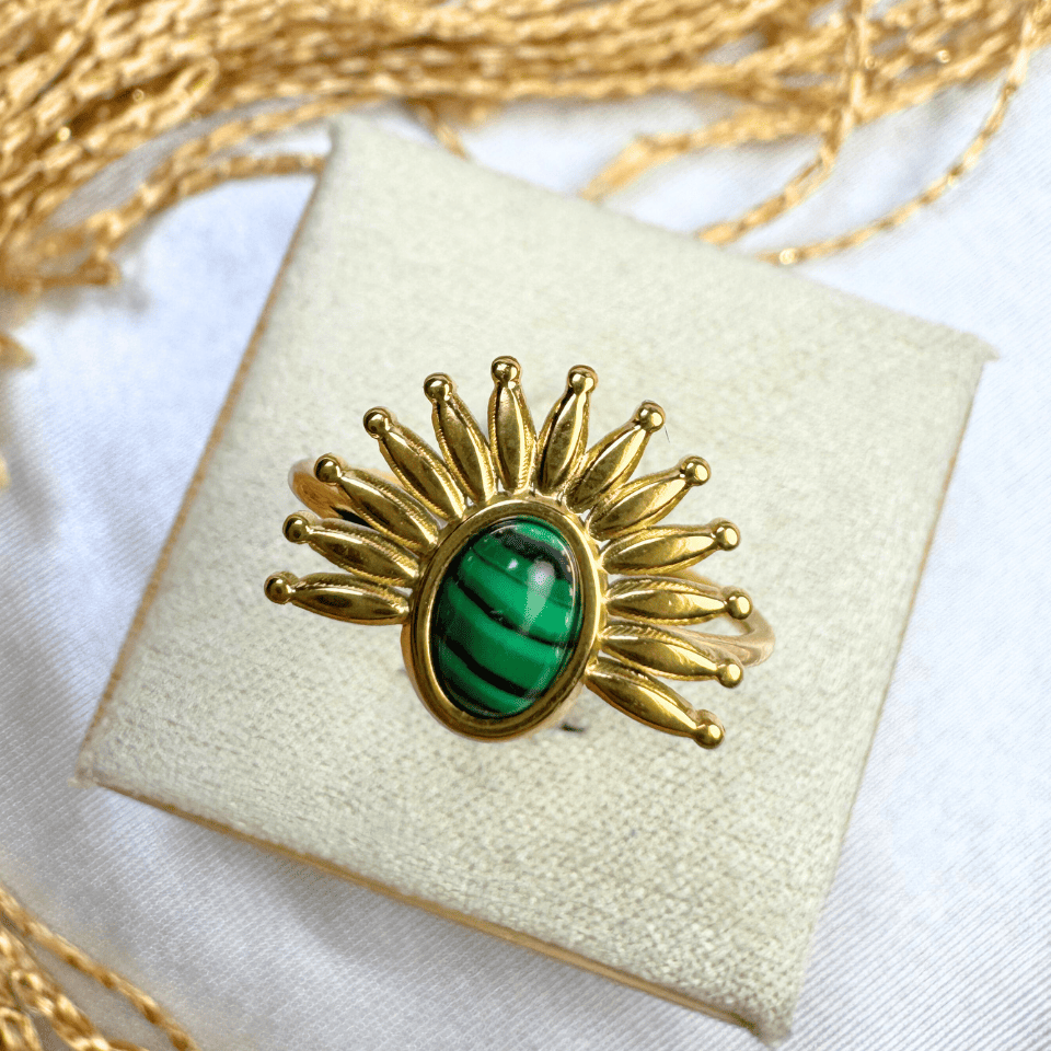 Gold brooch with green gemstone on a white cushion