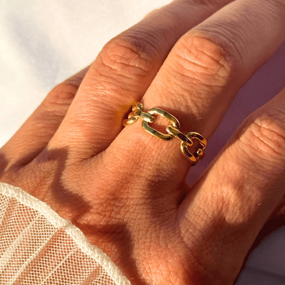 Gold chain ring on a person's finger with a blurred background