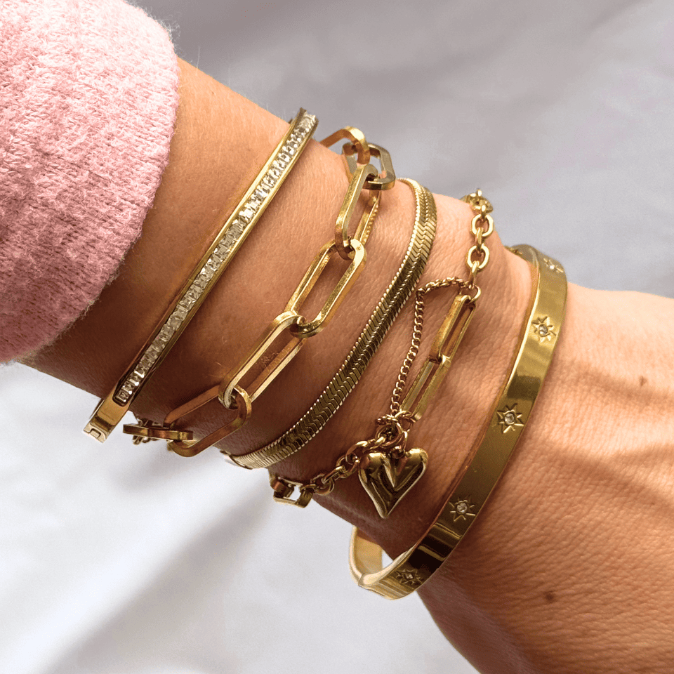 Gold bracelets on a wrist with a blurred background