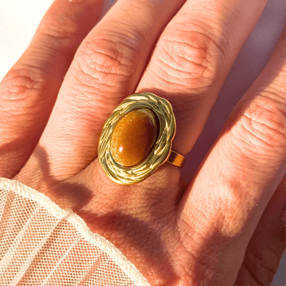 Gold ring with a brown stone on a hand