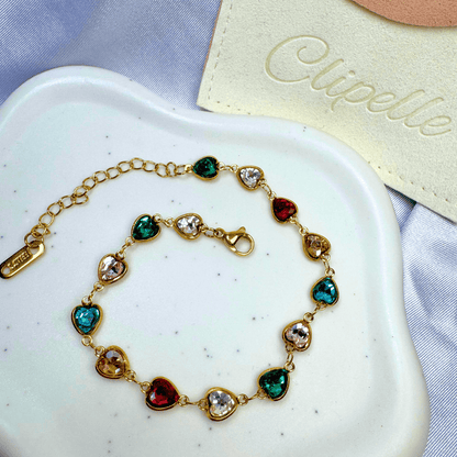 Gold bracelet with colorful gemstones on a white plate, with 'Elipelle' branding in the background.