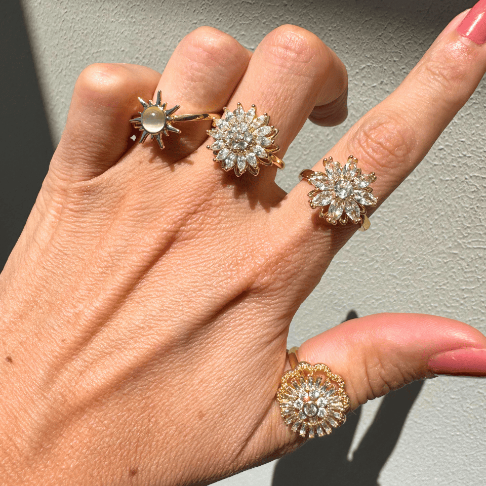 Hand wearing three diamond rings on a neutral background