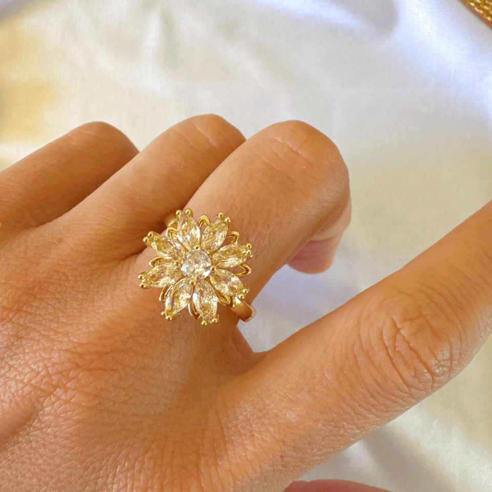 Gold ring with a diamond on a person's finger against a white background