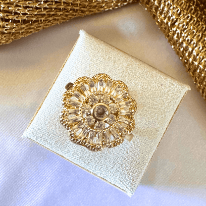 Gold floral brooch on a white box with gold ribbon