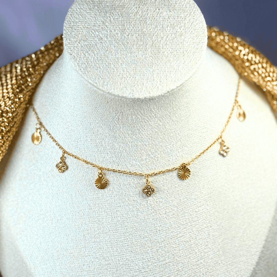 Gold necklace with small pendants on a mannequin bust.