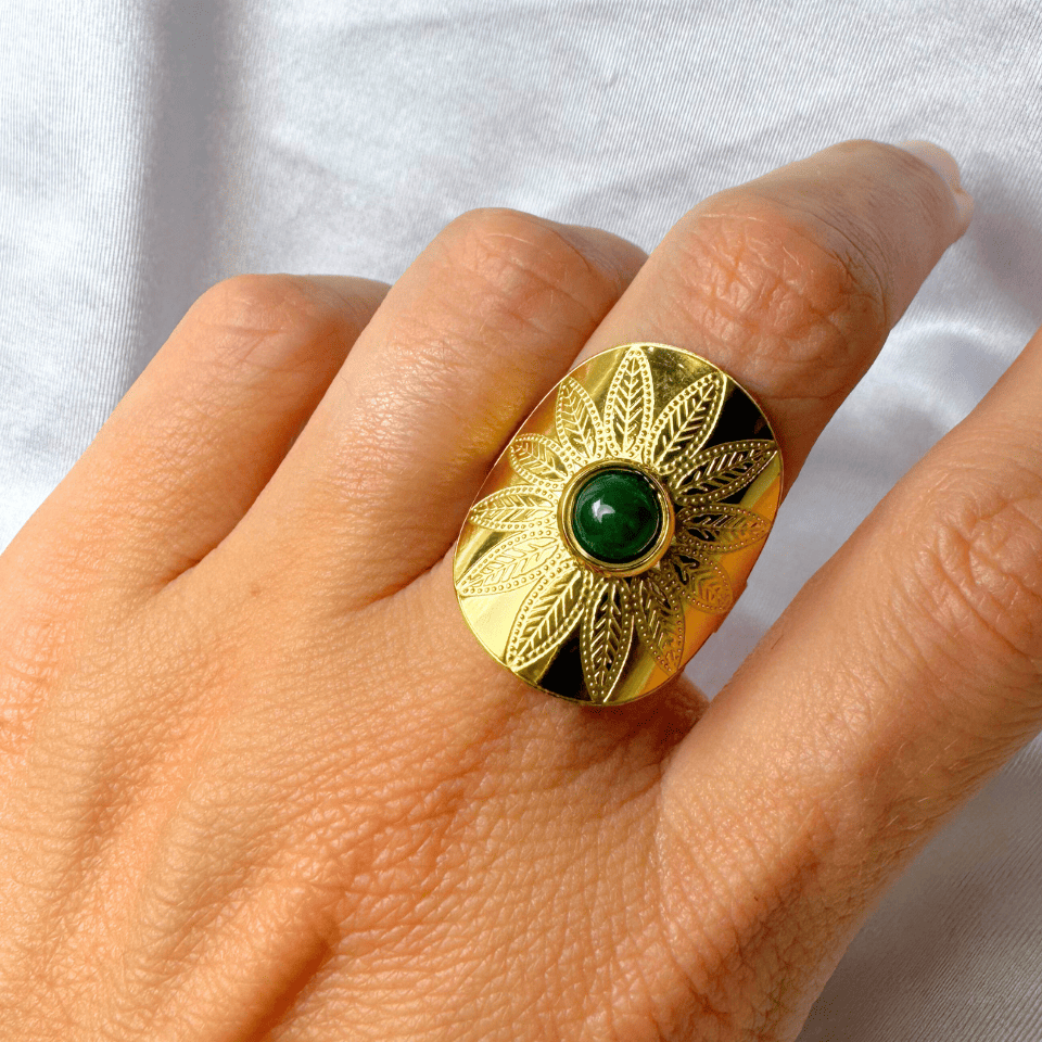 Gold chain necklace with shell and leaf pendants worn by a person in a white shirt.