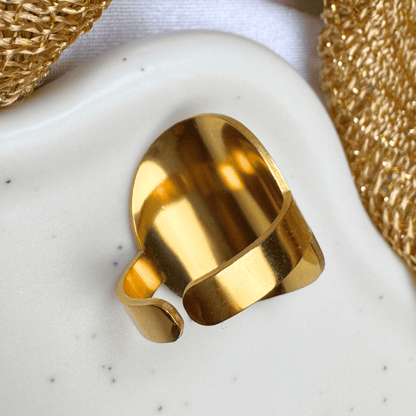 Gold ring on a textured white surface with gold mesh in the background