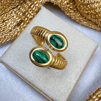 Pair of gold rings with green gemstones on a white box