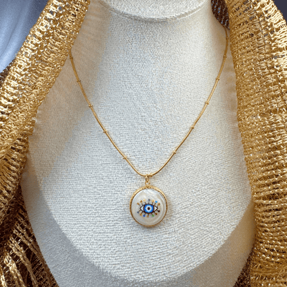 Gold necklace with an eye-shaped pendant on a mannequin bust.