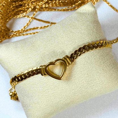 Gold bracelet with heart-shaped clasp on a white cushion