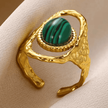 Gold ring with a green gemstone on a beige background