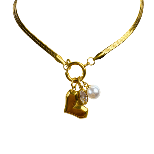 Gold necklace with heart-shaped charm, diamond, and pearl on a white background