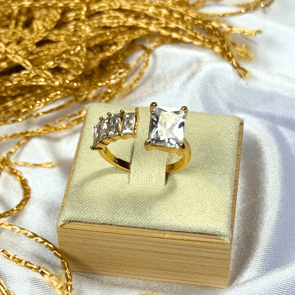Gold rings with gemstones on a gold box against a white background
