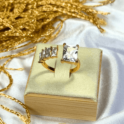 Gold rings with gemstones on a gold box against a white background