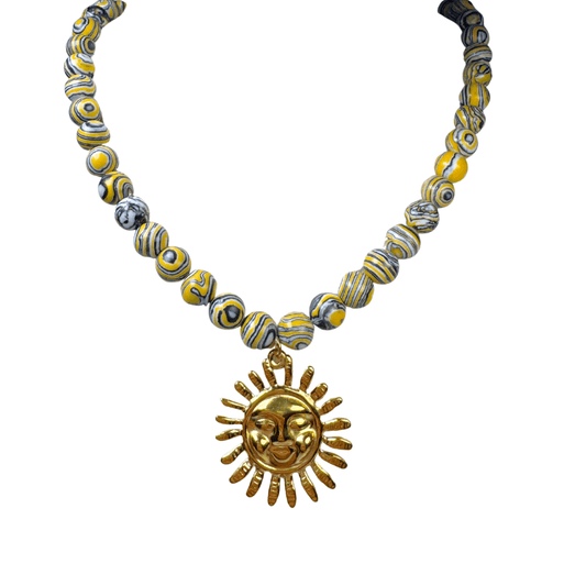 Necklace with yellow and gray beads and a gold sun pendant on a white background