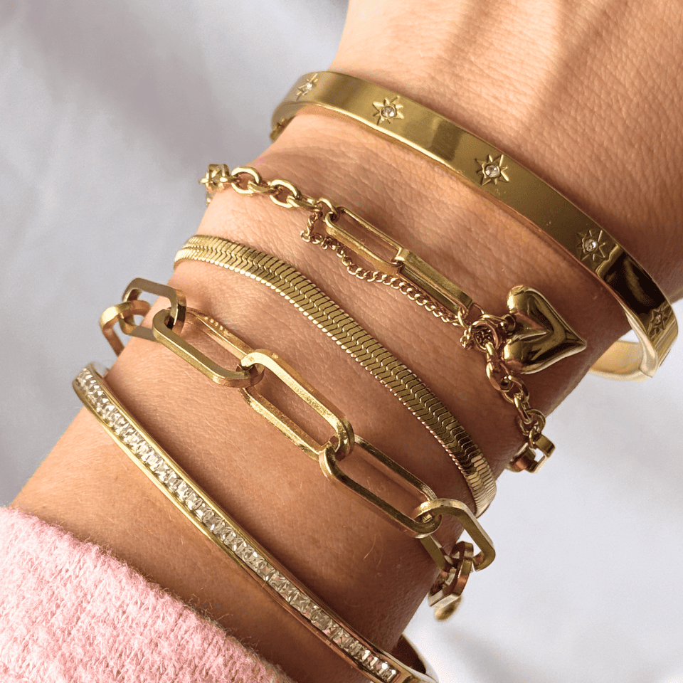 Gold bracelets on a wrist with a light background