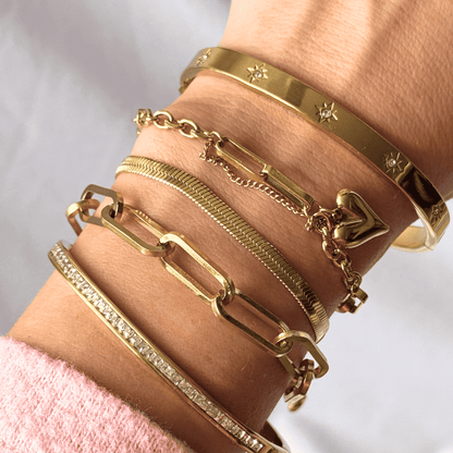 Gold bracelets on a wrist with a light background
