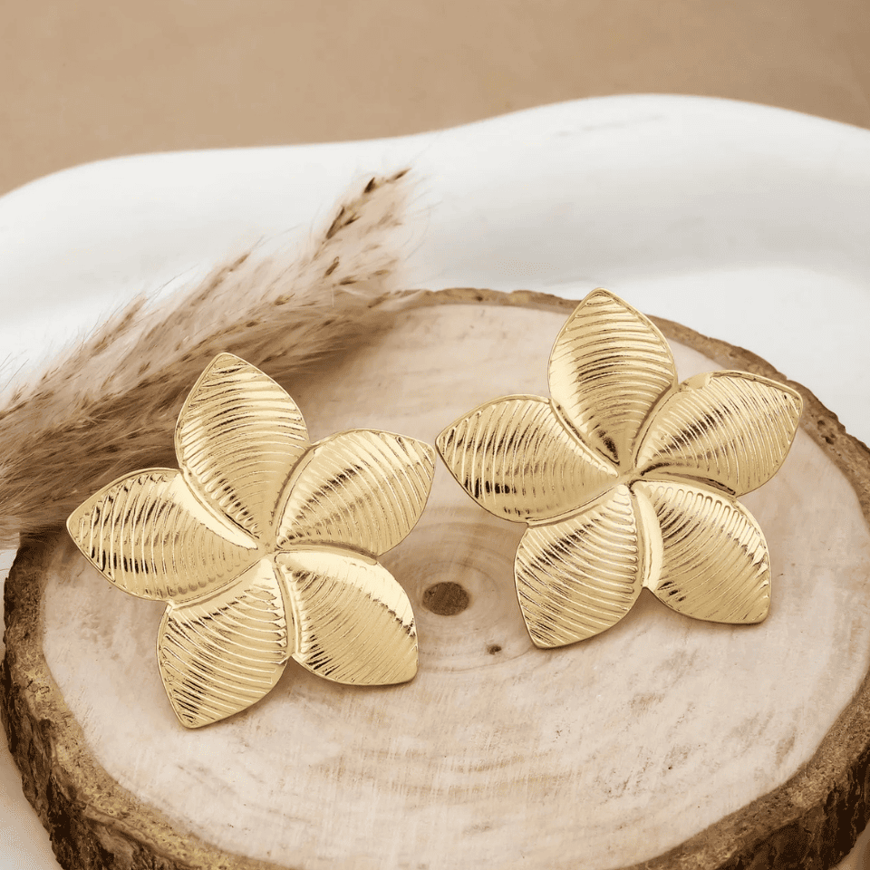 Gold flower-shaped earrings on a wooden surface