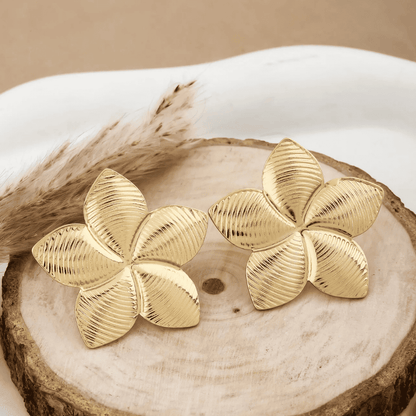 Gold flower-shaped earrings on a wooden surface