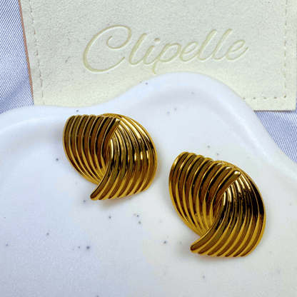 Gold earrings on a white surface with 'Clipelle' branding in the background
