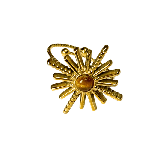 Gold sunburst ring with a central gemstone on a white background
