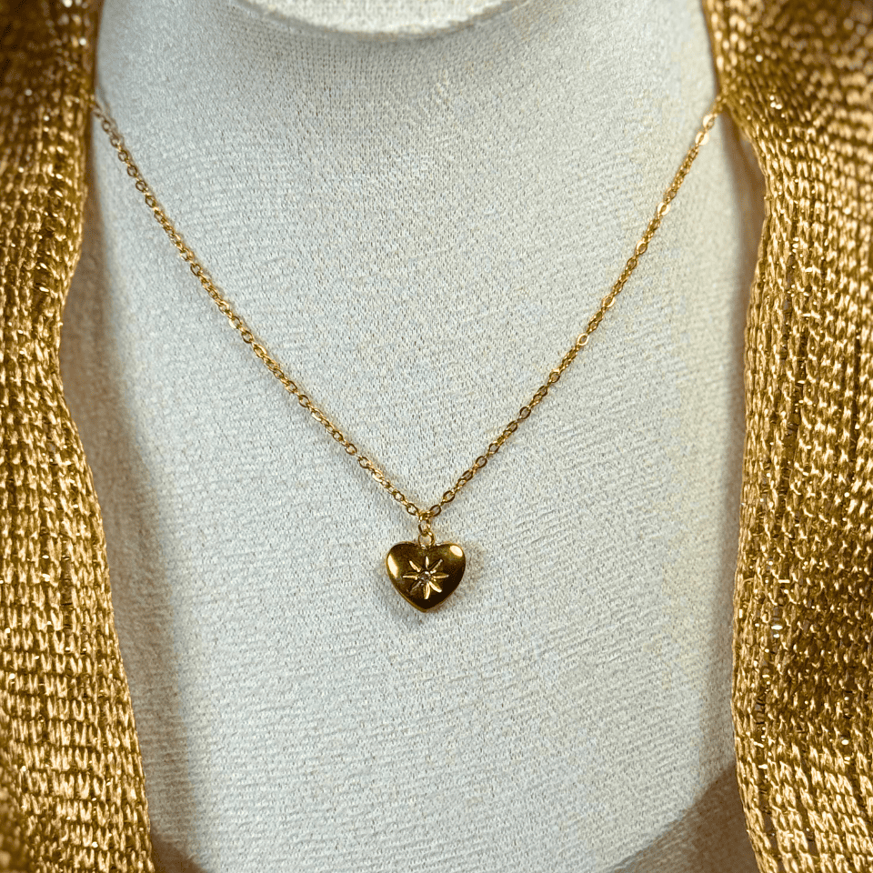 Gold necklace with a heart pendant on a mannequin bust.