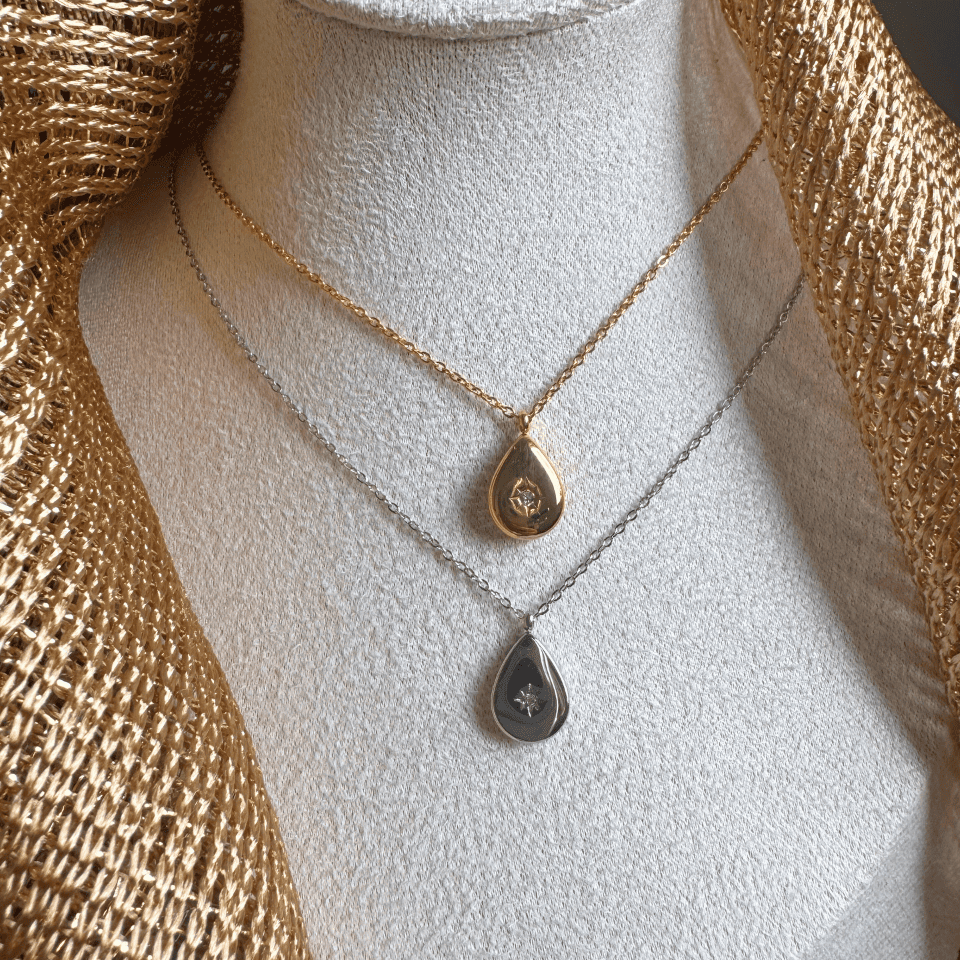 Two gold necklaces with teardrop pendants on a mannequin bust.