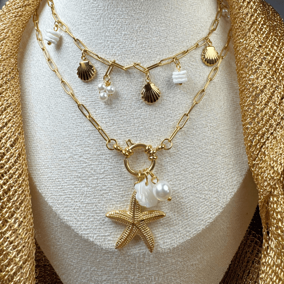 Gold necklace with starfish and shell charms on a mannequin bust.