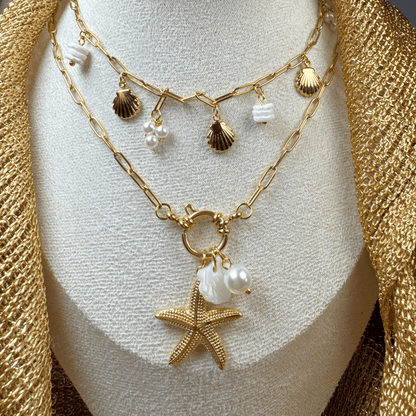 Gold necklace with starfish and shell charms on a mannequin bust.