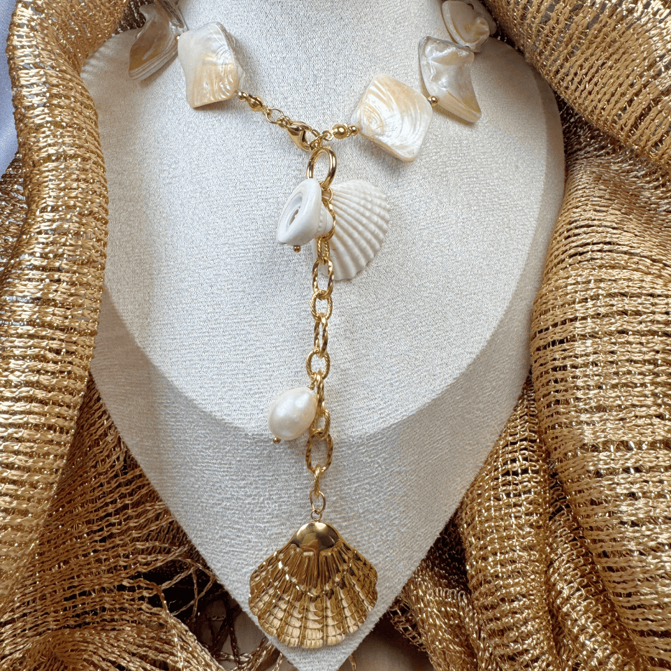 Necklace with shell and pearl decorations on a textured gold surface