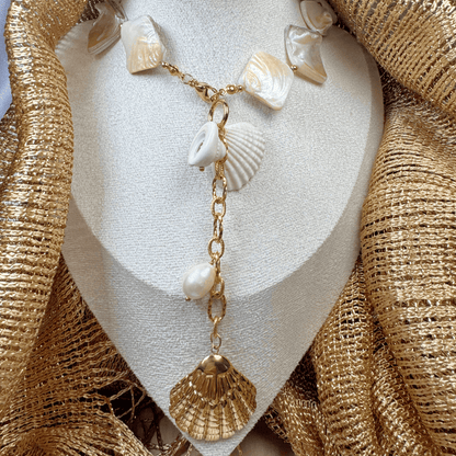 Necklace with shell and pearl decorations on a textured gold surface