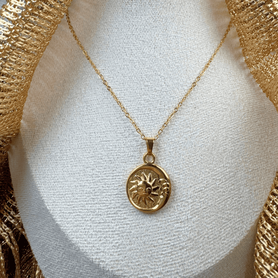 Gold necklace with a sun pendant on a white mannequin bust.