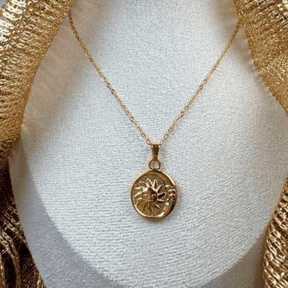Gold necklace with a sun pendant on a white mannequin bust.