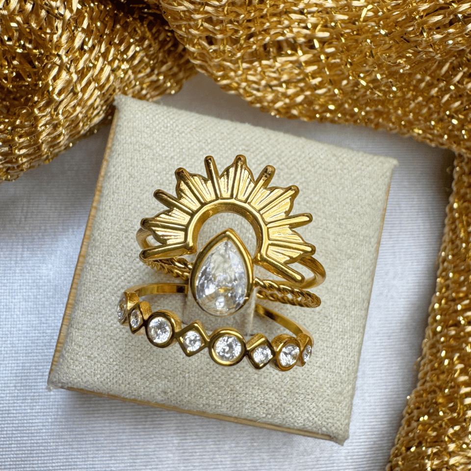 Gold ring with a central diamond on a beige jewelry box, surrounded by gold fabric.