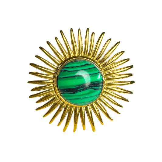 Gold sunburst brooch with a green gemstone center on a white background