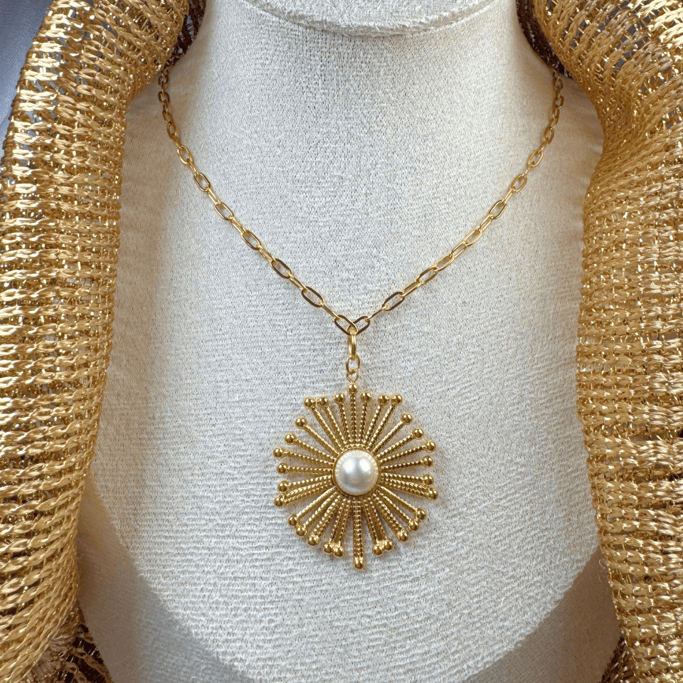 Gold necklace with a sunburst pendant on a mannequin bust.