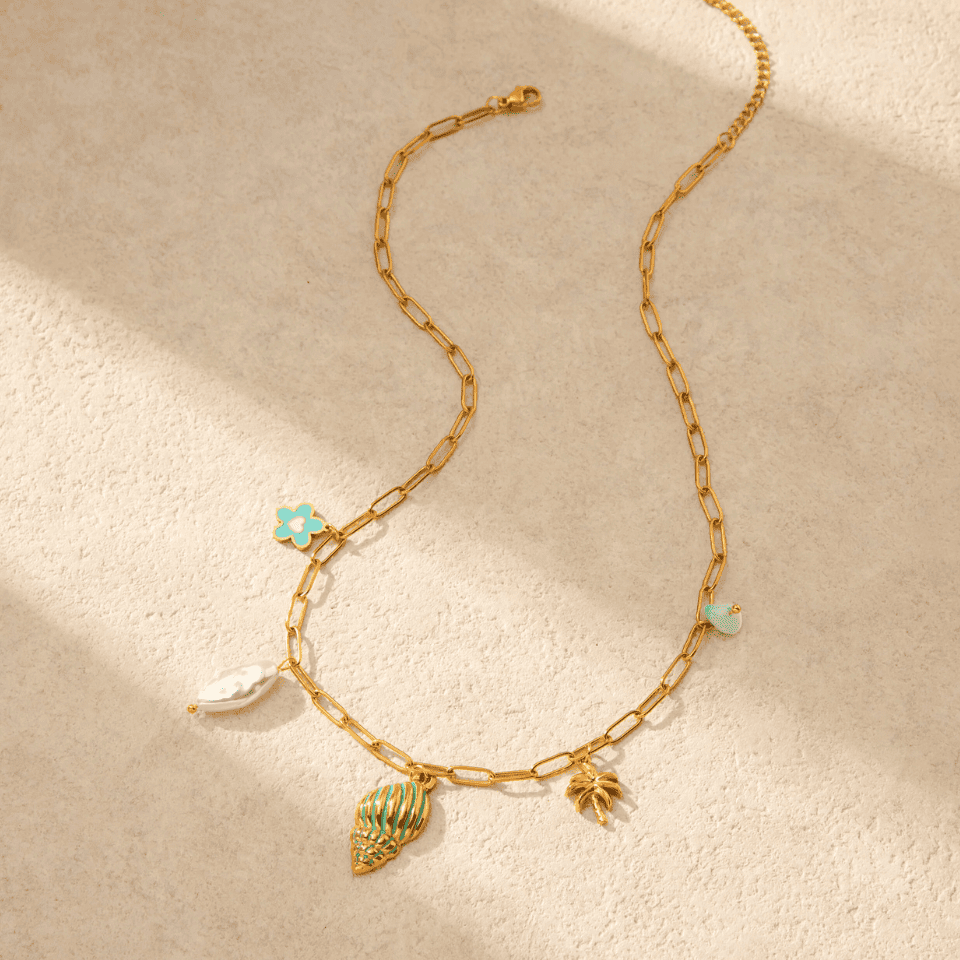 Gold chain necklace with charms on a beige background