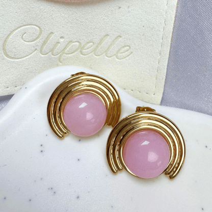 Pink earrings with gold accents on a white surface with 'Clipelle' branding.
