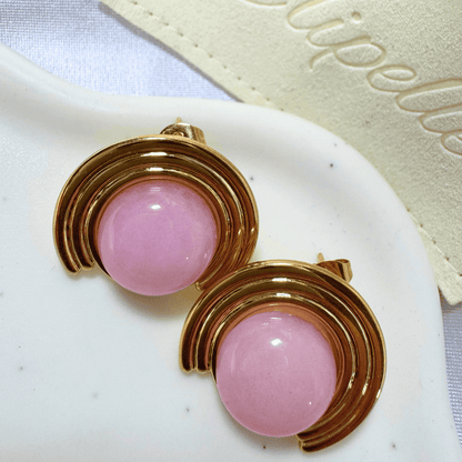 Pink earrings with gold accents on a white surface