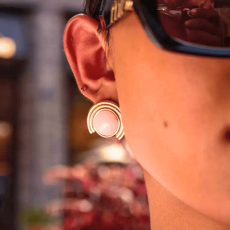 Close-up of an ear with a gold hoop earring against a blurred background