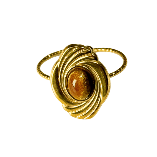 Gold ring with a central gemstone on a white background