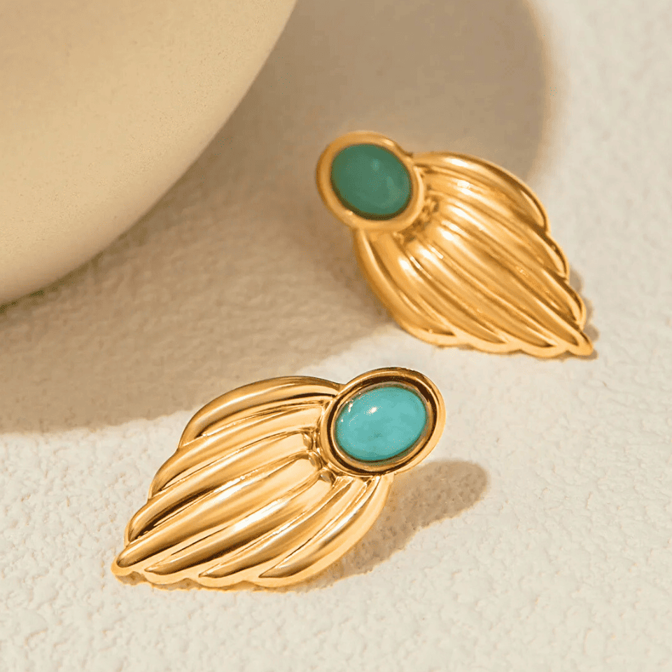 Gold earrings with turquoise stones on a beige background