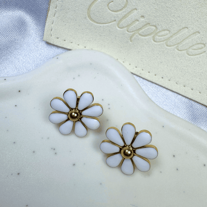 White flower-shaped earrings with gold centers on a white surface with 'Elipelle' branding.