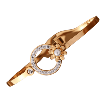 Gold bracelet with floral design and pearl center on a white background