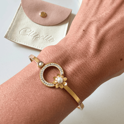 Gold bracelet with floral design on wrist, Clipette pouch in background