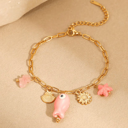 Gold bracelet with pink and gold charms on a beige background