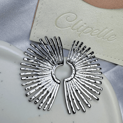 Silver hair clip on a gray fabric background with 'Elipelle' branding.