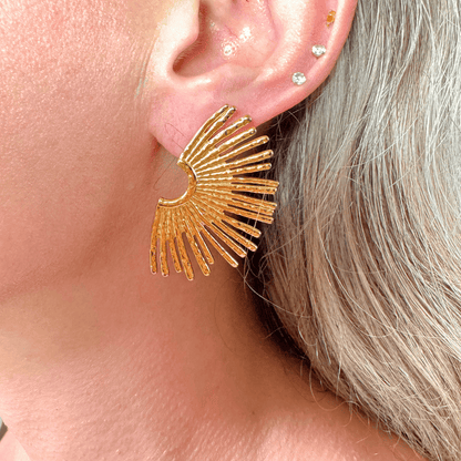Gold earrings worn by a person with gray hair